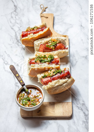 Chilean and Argentinian food. Traditional choripan with spicy pebre, chorizo sandwich with chorizo sausages and bread. 106271586