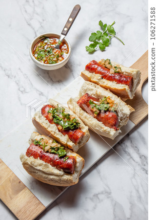 Chilean and Argentinian food. Traditional choripan with spicy pebre, chorizo sandwich with chorizo sausages and bread. 106271588