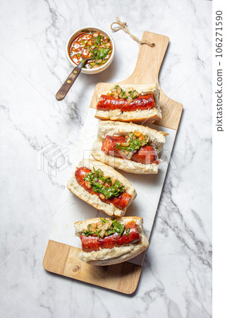 Chilean and Argentinian food. Traditional choripan with spicy pebre, chorizo sandwich with chorizo sausages and bread. Chilean and Argentinian food. Traditional choripan with spicy pebre, chorizo sandwich with chorizo sausages and bread. 106271590