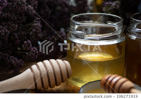 fresh natual  linden honey in glass jar with wooden  honey spoons around herb flowers. close up 106271919