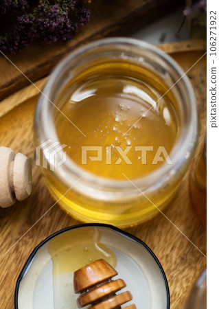 fresh natual  linden honey in glass jar with wooden  honey spoons around herb flowers. flat lay 106271922