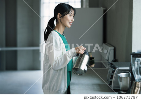 Woman brewing coffee in a stylish kitchen Woman brewing coffee in a stylish kitchen 106273787