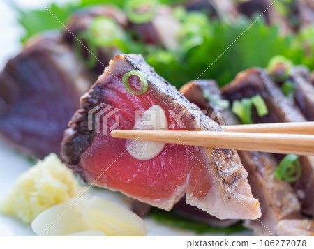 用筷子夾起烤好的鰹魚放在盤子裡 用筷子夾起烤好的鰹魚放在盤子裡 106277078