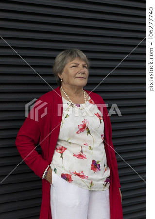 Closeup Real Senior Old 70s Pensioner, Dark Wall on Background. Portrait Of Kind Relaxed Elderly Woman Outdoor, Copy Space For Text. Authentic Lifestyle Vertical Plane. 106277740