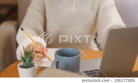 Home lifestyle concept, Young woman working on laptop and writing data in notebook at late night 106277889