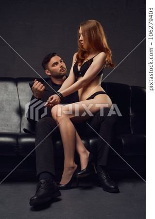 Frowning man banding a woman by hands sitting on his knees in dark studio Frowning man banding a woman by hands sitting on his knees in dark studio 106279403