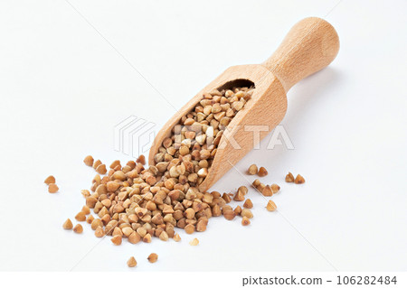 Wooden scoop of roasted buckwheat on a white background. Wooden scoop of roasted buckwheat on a white background. 106282484