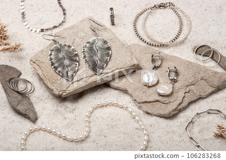 Beautiful Silver and Pearl Jewelry on white stones and sand. Various jewelry - bracelets, necklaces and rings. 106283268