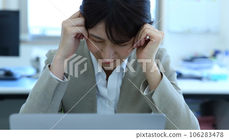 Image of a female office worker who is worried about holding her head 106283478