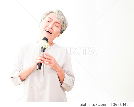 Happy senior asian woman singing with microphone in white background. Happy senior asian woman singing with microphone in white background. 106283491