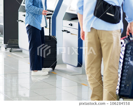 Men and women operating automatic check-in machines in the airport Men and women operating automatic check-in machines in the airport 106284558