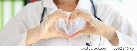Smiling female doctor showing heart gesture close up. Smiling female doctor showing heart gesture close up. 106284570