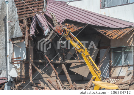 Heavy machinery demolishing the attic of a vacant house 106284712