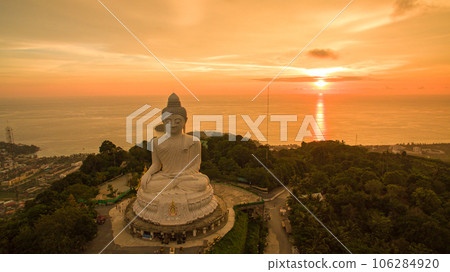 aerial view Phuket big Buddha in beautiful sunset. amazing sun shines through the yellow clouds impact on golden sea surface The beauty of the statue fits perfectly with the charming nature. aerial view Phuket big Buddha in beautiful sunset. amazing sun shines through the yellow clouds impact on golden sea surface The beauty of the statue fits perfectly with the charming nature. 106284920