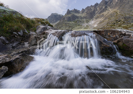 Beautiful alpine landscape with foreground waterfall and background rocky peaks, Slovakia, Europe Beautiful alpine landscape with foreground waterfall and background rocky peaks, Slovakia, Europe 106284943
