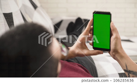Person holding a mobile phone with a green screen, ready to replace it with any content 106285636