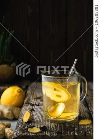 Ginger tea with lemon in a glass, close-up, ingredients for tea on a wooden vintage table. Prevention and support of immunity Ginger tea with lemon in a glass, close-up, ingredients for tea on a wooden vintage table. Prevention and support of immunity 106285881
