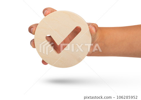 Check mark symbol on white isolated background. Big wooden round badge check stamp in hand close up. 106285952