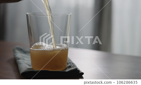 pour unfiltered apple cider into tumbler glass on wood table with copy space pour unfiltered apple cider into tumbler glass on wood table with copy space 106286635