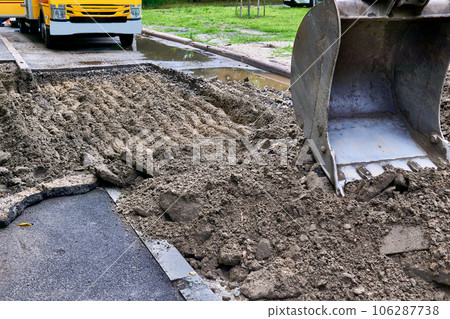 Excavator bucket picking up the ground, soil on road repair 106287738