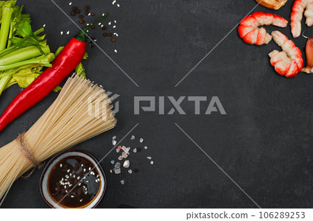 Ingredients for making fried noodles with shrimp, seafood, soy sauce and spices are placed on a black stone background. Top view, flat minimal design, asian food concept Ingredients for making fried noodles with shrimp, seafood, soy sauce and spices are placed on a black stone background. Top view, flat minimal design, asian food concept 106289253