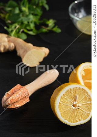 Lemon halves on a black wooden table, making lemon juice using a manual baking juicer, close-up, selective focus 106289312