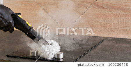 Manual cleaning of kitchen worktops with a hot steam cleaner. Selective focus with copy space. The concept of home cleaning and steam disinfection of the surface 106289458