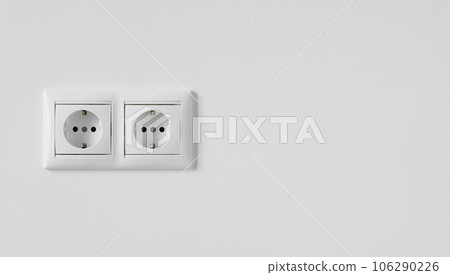 Block of two white plastic electrical outlets isolated on a white plastered wall. Electrical european outlet close up copy space 106290226