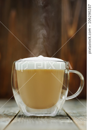 hot cappuccino in glass cup on grey wooden table hot cappuccino in glass cup on grey wooden table 106290287
