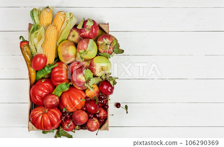 Fresh and colorful vegetables and fruits in a box on a white wooden table with copy space. Fresh food delivery from the store, seasonal vegetables. Fresh and colorful vegetables and fruits in a box on a white wooden table with copy space. Fresh food delivery from the store, seasonal vegetables. 106290369