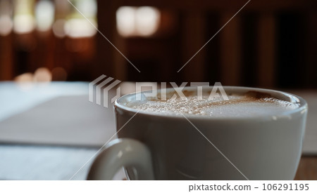 Cup with cappuccino coffee close-up, selective focus on the froth. Coffee break, rest in a cafe with a cup of aromatic latte coffee, an idea for a menu Cup with cappuccino coffee close-up, selective focus on the froth. Coffee break, rest in a cafe with a cup of aromatic latte coffee, an idea for a menu 106291195