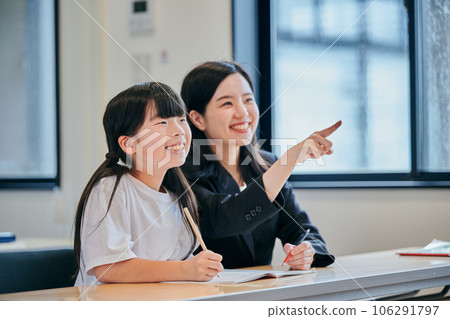 Elementary school girl and young cram school teacher staring at the whiteboard Elementary school girl and young cram school teacher staring at the whiteboard 106291797