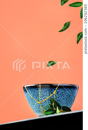 Bowl of green tea and levitation of tea leaves, against a background of burnt sienna. Selective focus on the cup. Refurbished ceramic cup, second life of things, recycling Bowl of green tea and levitation of tea leaves, against a background of burnt sienna. Selective focus on the cup. Refurbished ceramic cup, second life of things, recycling 106292360