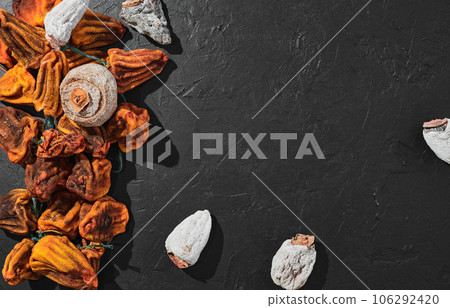 Dried persimmon on a black table. Top view of sweet dried persimmon. Traditional Japanese dessert cuisine. Naturally sun-dried persimmons 106292420