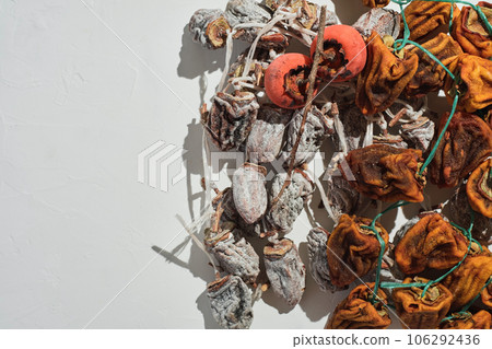 Sweet appetizing healthy dried persimmon. Top view of sun-dried persimmons on white concrete surface with copy space. Traditional dessert cuisine of the Caucasus and Asia 106292436