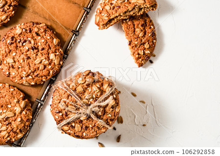 Oatmeal cookies with flax and sesame seeds on a baking sheet, white background with copy space. Top view of baked cookies, healthy breakfast. Homemade holiday baked goods Oatmeal cookies with flax and sesame seeds on a baking sheet, white background with copy space. Top view of baked cookies, healthy breakfast. Homemade holiday baked goods 106292858