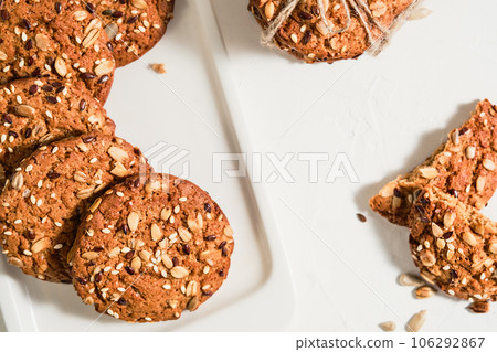 Top view of homemade oatmeal cookies with flax and sesame seeds on a white table. Healthy fitness food concept. Milk and biscuits, healthy breakfast food. Layout of Christmas cookies on a plate Top view of homemade oatmeal cookies with flax and sesame seeds on a white table. Healthy fitness food concept. Milk and biscuits, healthy breakfast food. Layout of Christmas cookies on a plate 106292867
