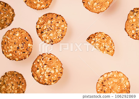 Homemade oatmeal cookies with flax, sunflower and sesame seeds on nude color wallpaper. Healthy fitness food concept. Milk and homemade cookies for breakfast layering on nude color background 106292869