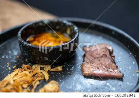 Beef tongue meat served on plate with fried garlic and egg yolk. Beef tongue meat served on plate with fried garlic and egg yolk. 106292941