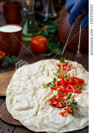 The process of making adana kebab (durum kebab) by the chef. Traditional Turkish or Arabic oriental kebab roll with salad and spices. Wooden background, close-up with shallow depth of field 106293085
