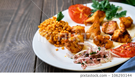 Light and delicious grilled chicken kebab, located on a platter with tomato and bulgur, decorated with cilantro sprigs. Healthy and tasty oriental cuisine. Close-up with copy space Light and delicious grilled chicken kebab, located on a platter with tomato and bulgur, decorated with cilantro sprigs. Healthy and tasty oriental cuisine. Close-up with copy space 106293144