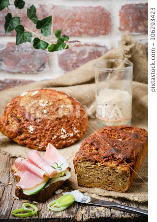 Sandwich with onions and ham on a slice of fresh bread. Sourdough rye yeast bread, cut into slices on a rustic wooden background. Healthy natural food. 106293423