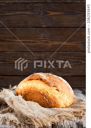 Loaf of homemade white milk sourdough bread, selective focus. Close-up, with copy space. Craft bread on a fabric lining, wooden background Loaf of homemade white milk sourdough bread, selective focus. Close-up, with copy space. Craft bread on a fabric lining, wooden background 106293645
