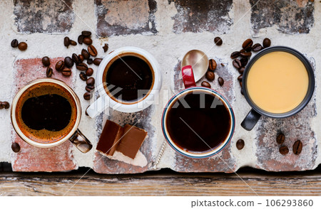 Several cups of espresso, ristretto and mocha on a brick windowsill. Top view of hot coffee, chocolate wedges and coffee grains. Background idea Several cups of espresso, ristretto and mocha on a brick windowsill. Top view of hot coffee, chocolate wedges and coffee grains. Background idea 106293860