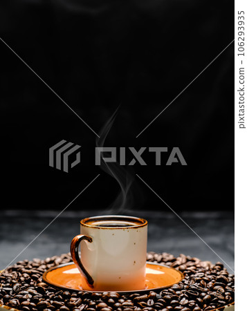 Cup with coffee espresso arranged on a dark background. Roasted coffee beans are located around a cup of coffee.Close up, selective focus Cup with coffee espresso arranged on a dark background. Roasted coffee beans are located around a cup of coffee.Close up, selective focus 106293935