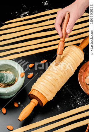 Cooking trdelnik. Baked delicacy on a skewer and charcoal dough with sugar, cinnamon and vanilla. Christmas sweets, street food. Czech and Moravian cuisine. 106293938