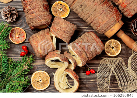 Delicacy from Trdelnik dough. Dough baked on a skewer and charcoal with sugar, cinnamon and vanilla. Christmas sweets, street food. Czech and Moravian cuisine. Delicacy from Trdelnik dough. Dough baked on a skewer and charcoal with sugar, cinnamon and vanilla. Christmas sweets, street food. Czech and Moravian cuisine. 106293945