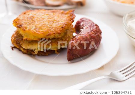 Potato pancakes with fried sausage on white plate Potato pancakes with fried sausage on white plate 106294781