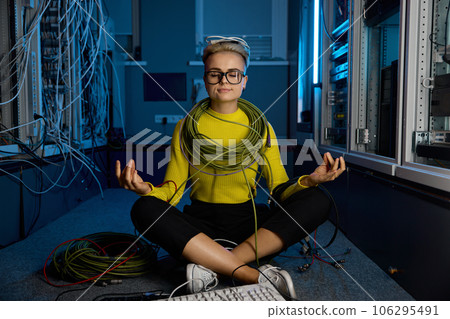 Calm female IT technician meditating in server room 106295491