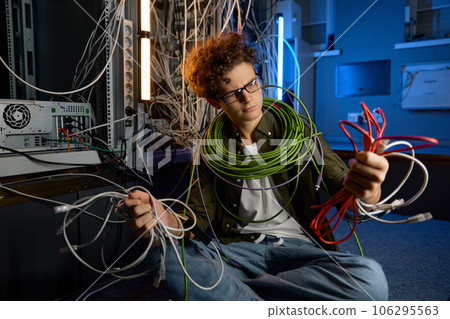 Confused IT networking engineer looking with disbelief on ethernet cables Confused IT networking engineer looking with disbelief on ethernet cables 106295563